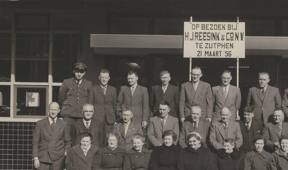 Middendrentse smeden met echtgenotes in 1956 op bezoek bij Reesink, Zutphen. Bovenste rij vlnr: Chauffeur..., x, Hendrik Schuring (Zwiggelte), x, Bertus Venema (Hooghalen), x, Albertus Speelman (Mantinge), Willem Smit (Wijster) en x. Middelste rij vlnr: x, Anton Koops (Hijken), x  Harm Ziengs (Witteveen), x , Klaas Mulder (Wijster), Albert Hummel (Spier), Hendrik Vrieling (Beilen), Hendrik Smit (Beilen) x en x. Voorste rij vlnr: A. Venema-Emmens, Roelofje Mulder-Nijsing, Roelfien Speelman-Boer, Jantje Ziengs-Hindriks, Grietje Smit-de Jonge, x, Grietje Hummel-Tijmes (Spier),  Femmichje Smit-Hidding (Beilen), Mevr. Koops-Schuring (Hijken) en J. (Dina) Vrieling-Rosing. Wie weet wie de anderen zijn? (Foto beschikbaar gesteld door Ge Prins-Hummel, Assen.)
